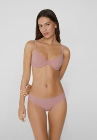 Měkká růžová souprava spodního prádla s podprsenkou s polstrováním a nastavitelnými ramínky, bezšvovými bikinami, vyrobená z hladkého, elastického materiálu.