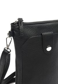 Svart läder crossbody-väska med texturerad yta, dragkedjestängning, silverfärgade detaljer och ett avtagbart rem. Har ett framfick med tryckknapp.