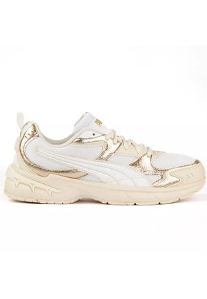 Zapatilla blanca y dorada de corte bajo con paneles de malla y cuero, diseño con cordones, suela gruesa y detalles sutiles de la marca en el lateral y el talón.