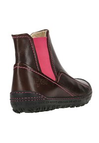 Braune Leder-Stiefelette mit pinken elastischen Einsätzen, kontrastierendem pinken Nähten und einer schwarzen Gummisohle mit geprägt gedrucktem Text.