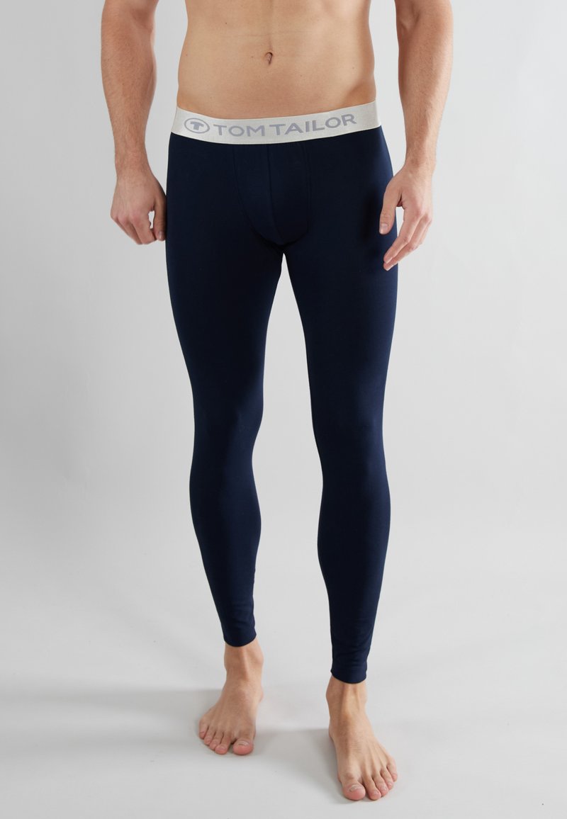 Leggings azul marino hechos de material elástico con una cinturilla gris claro que presenta el logo de "TOM TAILOR". Diseño ajustado, de longitud hasta el tobillo.