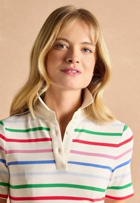 Kurzärmeliges, geripptes Poloshirt in Creme mit horizontalen Streifen in Rot, Grün, Pink und Blau; ausgestattet mit einem Knopfkraagen.