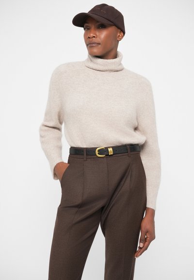 Μπεζ πλεκτό πουλόβερ με ψηλό λαιμό, υφασμάτινη αίσθηση; καφέ κομμένα παντελόνια με τσέπες; μαύρη ζώνη με χρυσό πόρπη; καφέ καπέλο.