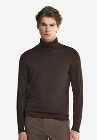 Mörkbrun polotröja i mjukt material, med lång ärm och en figurnära siluett. Slät textur och subtila designdetaljer.