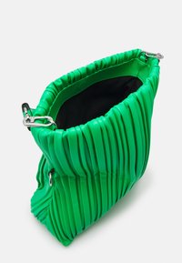 Vihreä pleidattu käsilaukku, joka on valmistettu sileästä materiaalista, mustalla sisäosalla, hopeisilla yksityiskohdilla ja ylhäältä avautuvalla sulkemisella.
