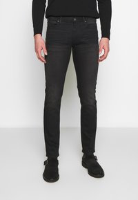 Svarta denimjeans med smal passform, med en klassisk design med fem fickor och subtil blekning. Matchas med svarta mockaskor.