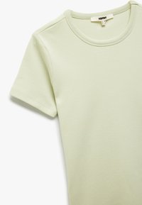 Lichtgroene katoenen t-shirt met een ronde hals en korte mouwen. Zachte textuur, met strakke lijnen en een eenvoudig, minimalistisch ontwerp.