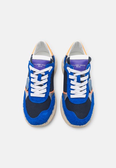 Ζευγάρι μπλέ και μαύρα αθλητικά παπούτσια με λευκές θηλιές, μωβ ταμπέλες στη γλώσσα, πορτοκαλί λεπτομέρειες και μπεζ σόλες, προοδευτικά από πάνω σε λευκό φόντο.