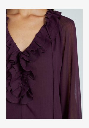 Lila Bluse mit tiefem V-Ausschnitt und Rüschensaum, aus glattem Stoff und mit Knopfdetails, die die Vorderseite hinunterlaufen.