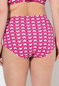 Roze high-waisted bikini onderstuk met een herhalend wit hartpatroon, een gladde textuur en een elastische tailleband voor comfort en pasvorm.