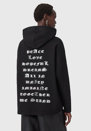 Hoodie noir avec du texte blanc et argent imprimé verticalement dans le dos, avec des phrases comme "PAIX" et "AMOUR". Tissu doux et texturé.