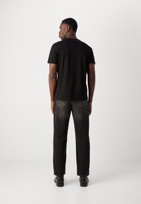 Black short-sleeve t-shirt made of soft cotton, paired with dark gray denim pants featuring a classic fit and subtle back pocket details.