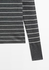 Szara koszula z długim rękawem w białe poziome paski, wykonana z miękkiej tkaniny, o dopasowanym kroju i starannie wykończonych mankietach.