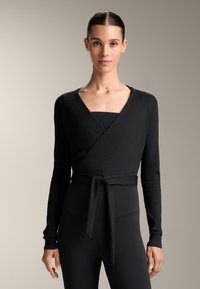 Fekete, puha anyagból készült, hosszú ujjú felcicomázott blúz, megkötős derékkal. Mély V-kivágása és bordázott textúrája van.