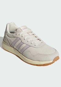 Světlé béžové tenisky Adidas s vrškem z mesh a semiše, třemi světle fialovými pruhy, polstrovaným límcem a podrážkou z gumové pryže.