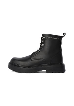 Botas de cuero negro hasta el tobillo con punta redonda, cordones en la parte delantera, ojales de metal y una tira de agarre. Cuentan con una suela de goma gruesa y un adorno con el logo.