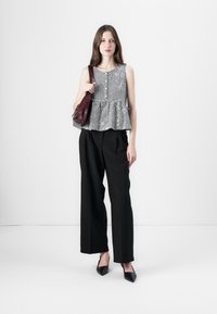 Čierno-biely kockovaný peplum top s okrúhlym výstrihom, skombinovaný s vysokými čiernymi nohavicami. Doplnkovaný bordovou kabelkou.