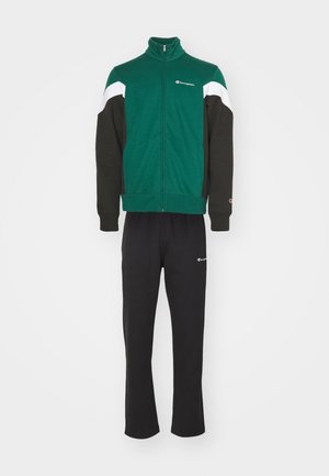 Giacca verde con zip e maniche nere, arricchita da dettagli bianchi, abbinata a pantaloni della tuta neri, entrambi con piccoli dettagli del logo.