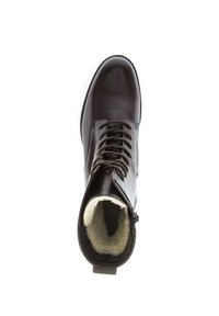 Botte en cuir marron foncé avec des lacets, doublure en fourrure douce et une languette à l'arrière pour un enfilage facile. Bout rond et finition lisse.
