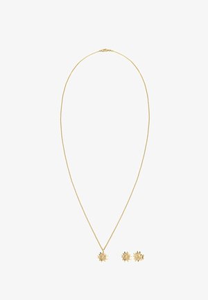 Collier doré avec un pendentif en forme de rayon de soleil, boucles d'oreilles assorties arborant un design similaire. Texture métallique lisse, chaîne délicate.