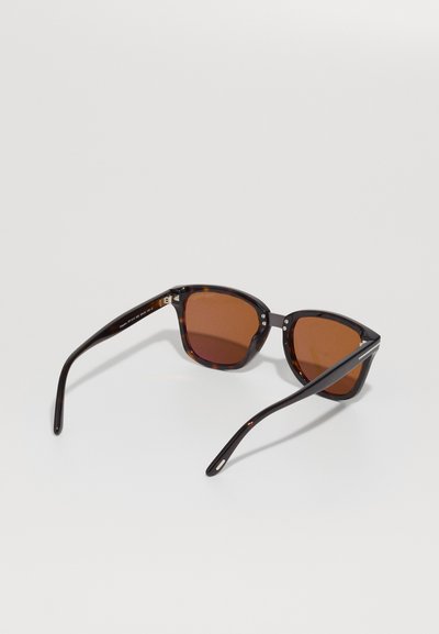 Polarized sunglasses with a glossy tortoiseshell frame, angular design, brown lenses, and sleek black arms. Metal accents on hinges.
