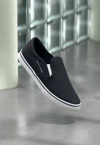 Παπούτσια τύπου Slip-on από καμβά σε ναυτικό μπλε χρώμα με λευκή ελαστική σόλα και αντίθετες λευκές λεπτομέρειες. Διαθέτουν λογότυπο της μάρκας στο πλάι.