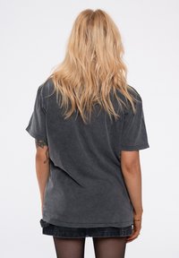 Dark grey oversized t-shirt made from soft cotton, featuring short sleeves and a relaxed fit. The fabric has a subtle, worn texture.