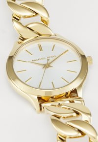 Montre-bracelet Michael Kors couleur or avec cadran blanc, index horaires dorés minimalistes et bracelet à gros maillons.