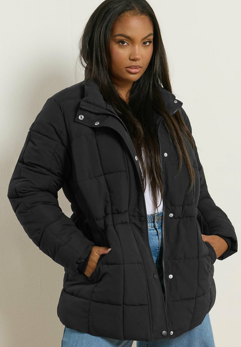 Doudoune noire avec un design matelassé, fermeture éclair sur le devant, boutons-pression et poches latérales. Caractéristiques : col montant et coupe décontractée.