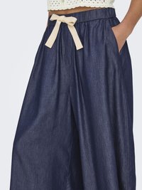 Marineblauwe wijde broek met een gladde textuur, voorzien van een crèmekleurige lintstrik, elastische tailleband en zijzakken.