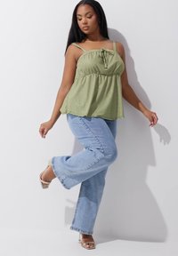 Top de peplum de cuadros vichy verdes con tirantes ajustables, cintura ceñida y corte relajado, combinado con jeans acampanados de color azul claro y sandalias de tacón nude.