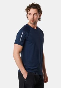 Marineblå atletisk T-shirt i glat syntetisk stof, med korte ærmer, rund hals og reflekterende detaljer på skulderen.