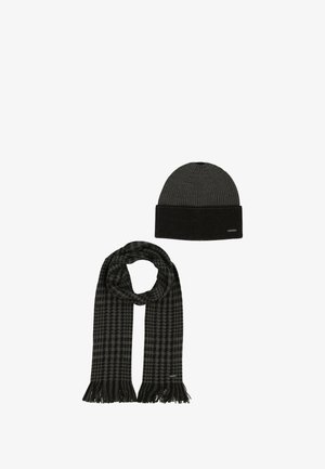 Melna ribots adītas cepure ar atlocītu malu un atbilstošs rūtainas raksta šalle ar bārkstīm malās. Abi priekšmeti ir mīksta tekstūra.