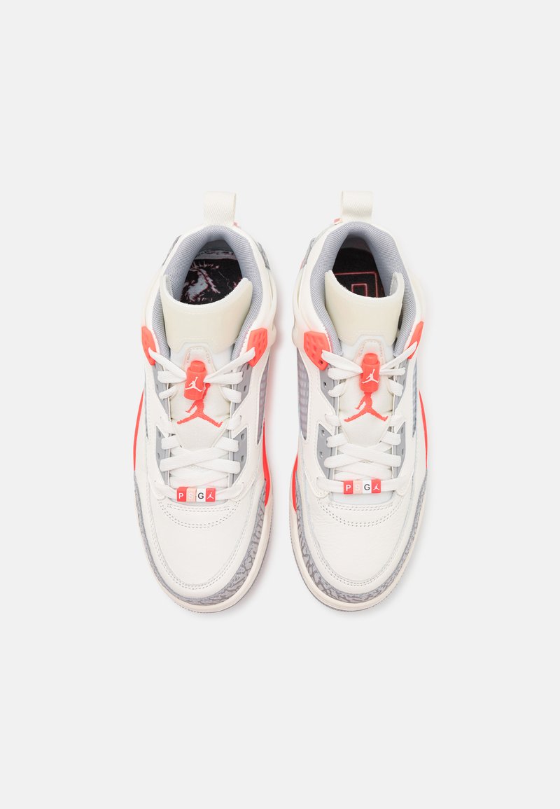 Weiße und graueSportschuhe mit roten Akzenten, die ein strukturiertes Design, eine Schnürverschluss und sichtbare Markenkennzeichnung auf der Zunge aufweisen.