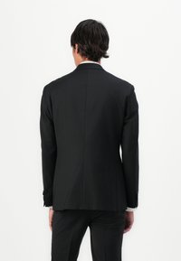 Black tailored suit jacket with a smooth, matte texture. Features two back vents and sleek accents. Shown from the back against a white background.