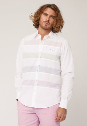 Camicia bianca con bottoni caratterizzata da strisce orizzontali in colori pastello chiari, con un piccolo logo blu e una texture di tessuto liscia.