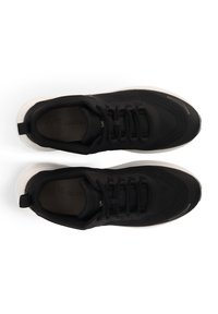 Schwarze Sportschuhe mit einem glatten Stoffobermaterial, strukturierten Details und einer weißen, gepolsterten Sohle. Mit Schnürdesign und Zuglasche an der Ferse.