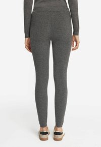 Leggings grigi realizzati in un tessuto morbido e testurizzato. Presentano un alto girovita e si stringono alla caviglia, abbinati a scarpe casual.