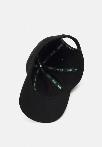 Casquette de baseball noire avec une visière courbée et une bande intérieure verte comportant le logo de la marque répété. Fabriquée en tissu avec une texture lisse.