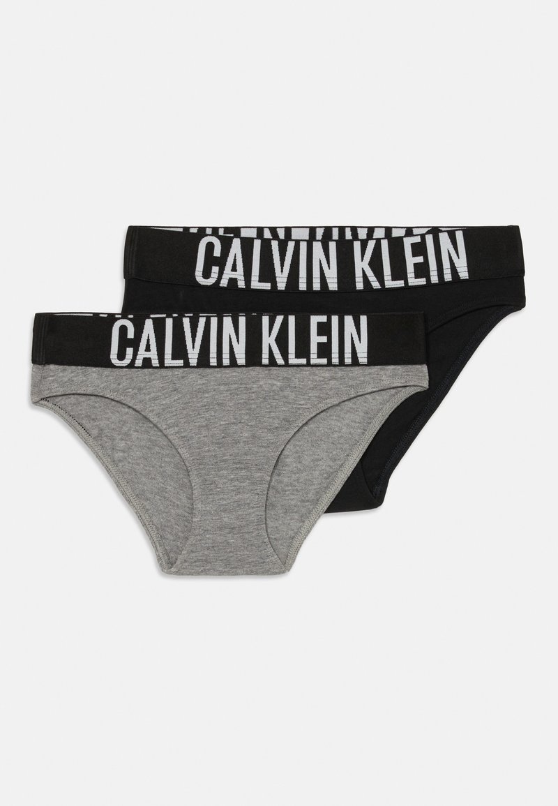 Dois pares de cuecas femininas: uma cinza, outra preta. Ambas apresentam uma cinta elástica larga com "CALVIN KLEIN" impresso em branco. Material de algodão suave.