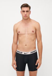 Sorte boxer briefs med en bred elastisk talje med et fremtrædende Nike-logo i hvidt. Glat, strækbart stof; tætsiddende design.