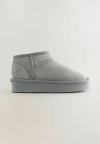Grå suede ankelstøvle med rund tå, subtil syning og en tekstureret gummisål. Blødt materiale og minimalistisk design.
