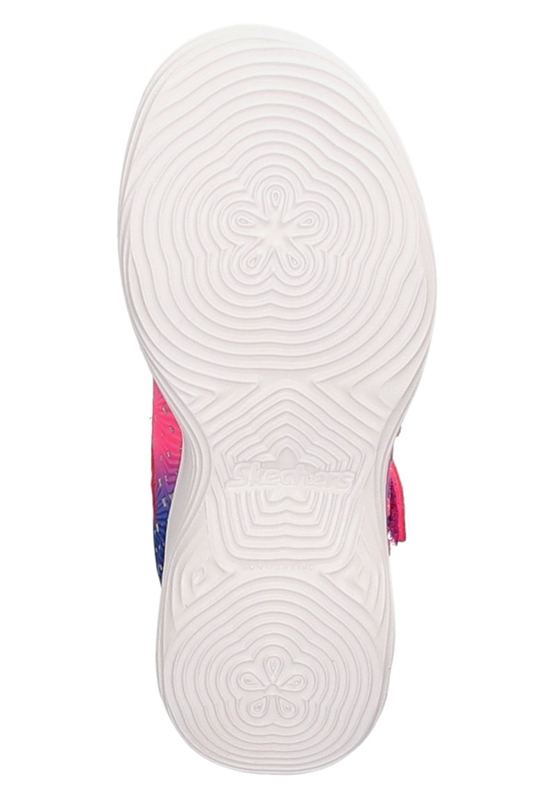 Suela blanca de una zapatilla con patrones circulares concéntricos y diseños de huellas florales, mostrando parcialmente bordes superiores en rosa y azul.