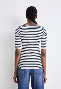 Gestreiftes T-Shirt in Marineblau und Creme, mit einer taillierten Schnittform und Dreiviertelärmeln. Glatte Textur mit rundem Ausschnitt.