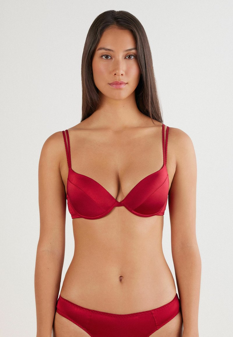 Roter Sat BH mit vorgeformten Cups, verstellbaren Doppelträgern und subtilen Nahtdetails. Glatte Textur und taillierte Passform. Einfaches Design.