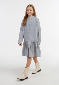 Båndet skjorte kjole med en udfladskørt, lavet af letvægtsstof. Båret med beige cowboy støvler.