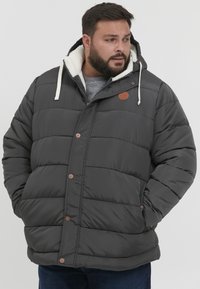 Padded gray jacket with a hood, featuring a fleece lining, button closures, and a brown logo patch. Designed for warmth and comfort.