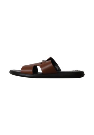 Sandale slide en cuir marron à bout ouvert avec semelle plate noire et motif découpé sur la bride supérieure.