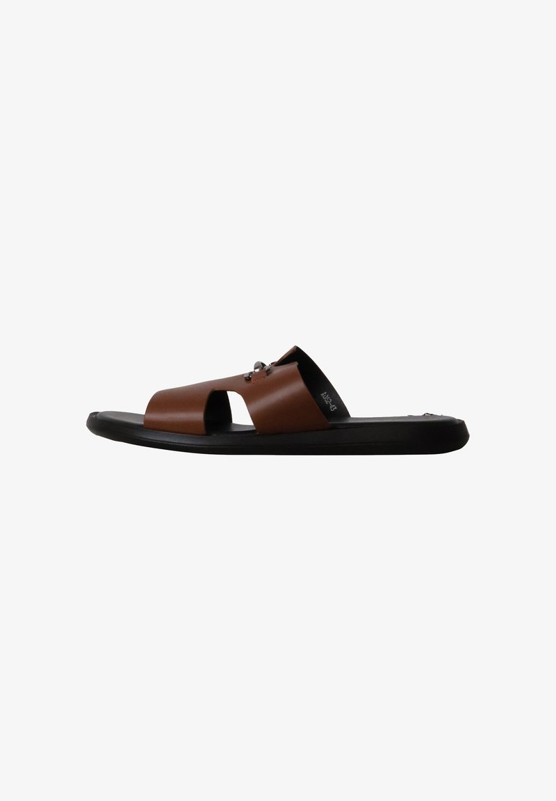 Sandale slide en cuir marron à bout ouvert avec semelle plate noire et motif découpé sur la bride supérieure.