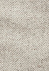 Herringbone tkanina v béžových a světle šedých odstínech, s měkkou texturou a výrazným Chevron vzorem, těsně tkaná s viditelnými vlákny.